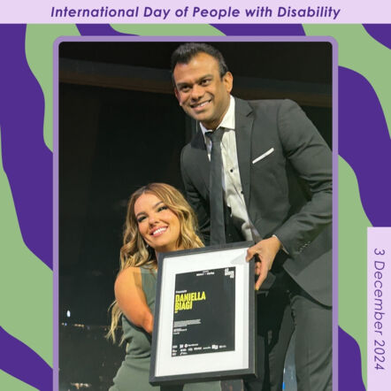 Patterned purple and green background with a photo in the centre of Daniella, Purple Orange Board Treasurer, at the InDaily 40 Under 40 awards. Daniella is standing with a man, holding a framed award, posing for a photo. Text on border: International Day of People with Disability. 3 December 2024.