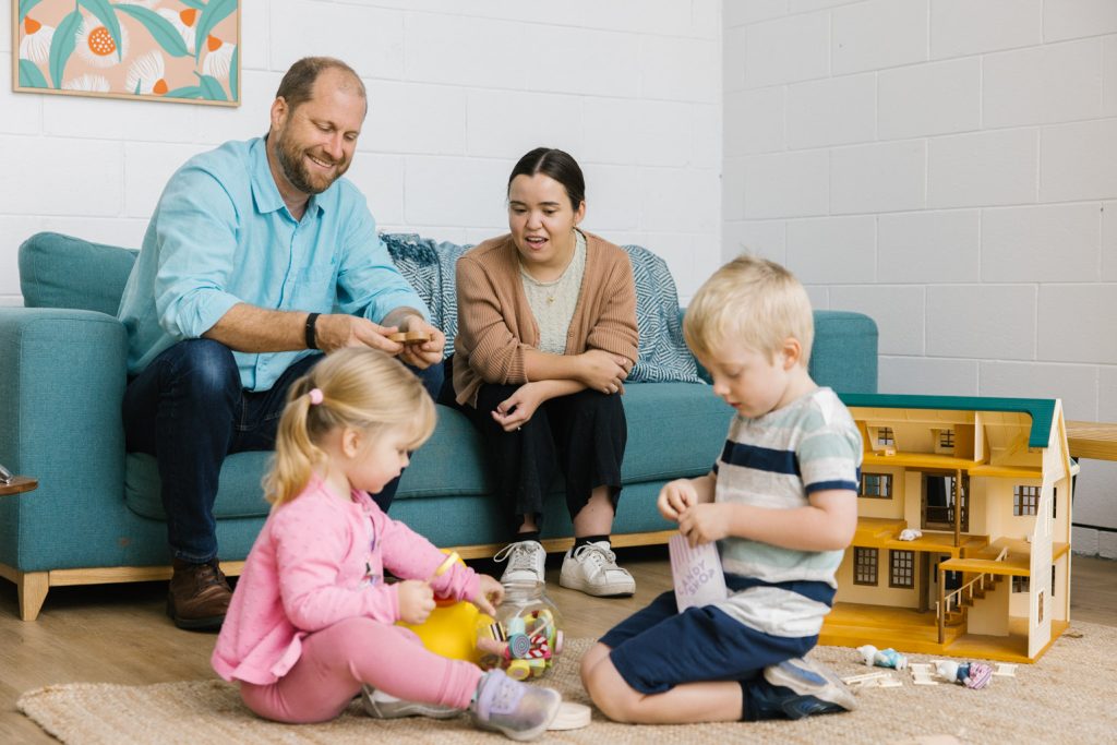 A family - dad, mum, a boy and a girl - are talking and playing together.