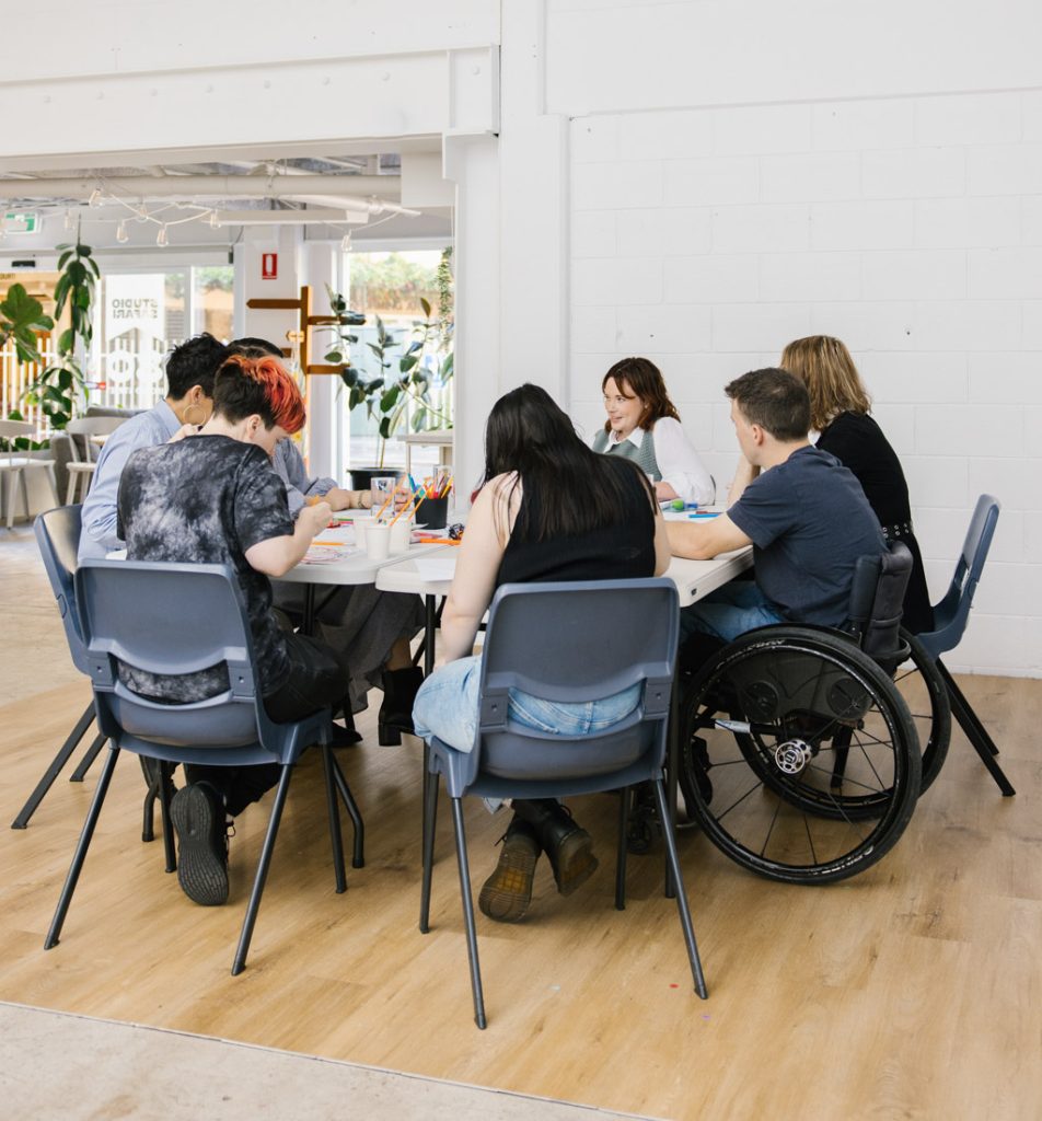 Group of people sit at a table doing an activity.